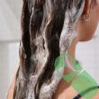 Woman washing hair with Deep Steep Coconut Oil High Shine Shampoo in shower